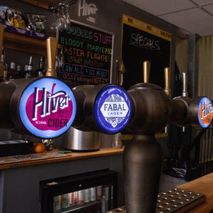 Row of beer taps with branded covers in a bar setting