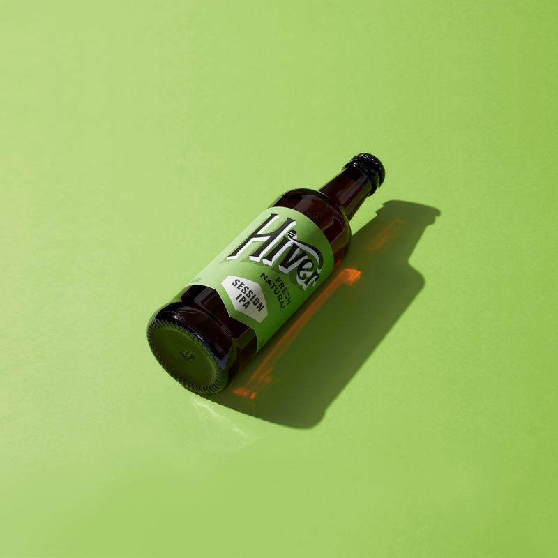 Single bottle of Hiver Session IPA lying on a green studio background