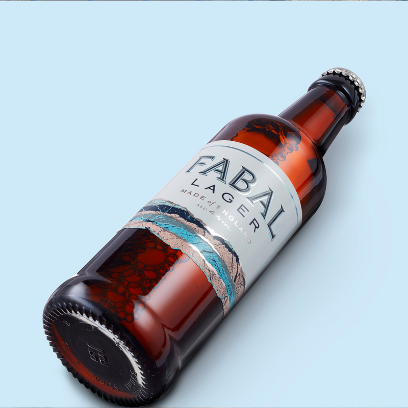 Single bottle of Fabal Lager lying on a light blue background